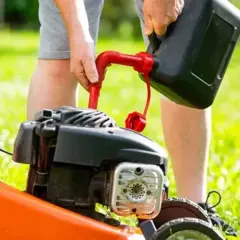 Osoba nalewa paliwo do kosiarki. Prawidłowe paliwo do kosiarki to klucz do jej długiej pracy.