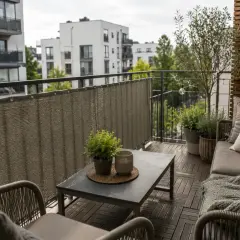 Nowy, przytulny balkon po remoncie. Meble, rośliny i osłona tworzą idealne miejsce do relaksu.